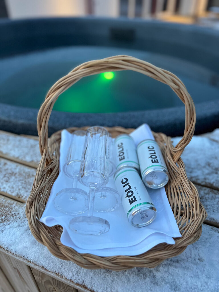 a basket with small boxes of wine and wine glasses in front of the hot tub at tofta herrgård