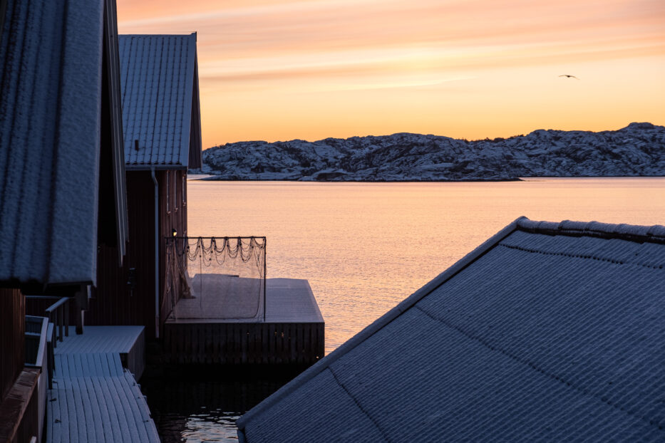 a golden sunrise over icy cold houses and the sea in sweden