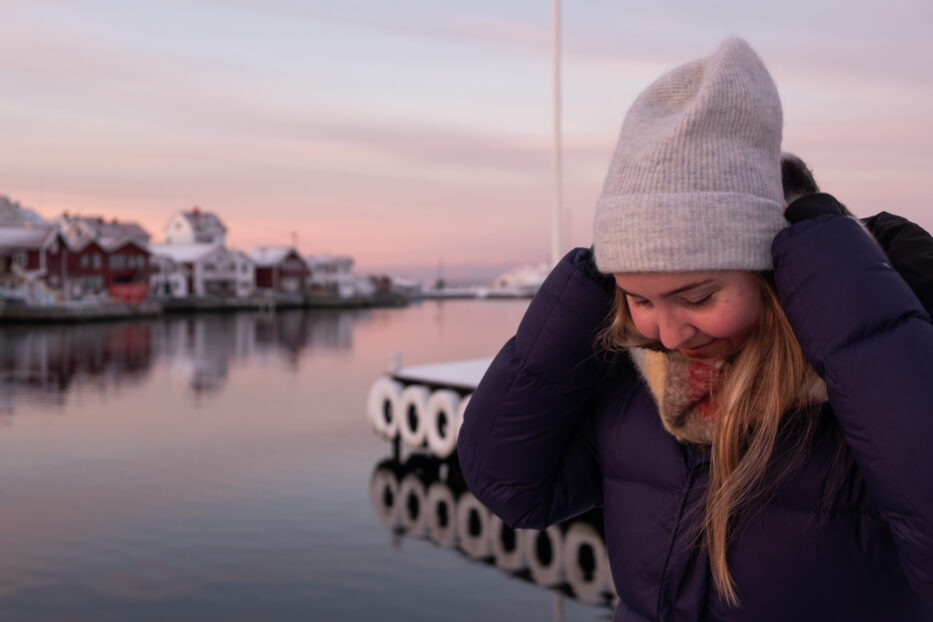 woman adjusting woolen hat in front of the sea at klädesholmen