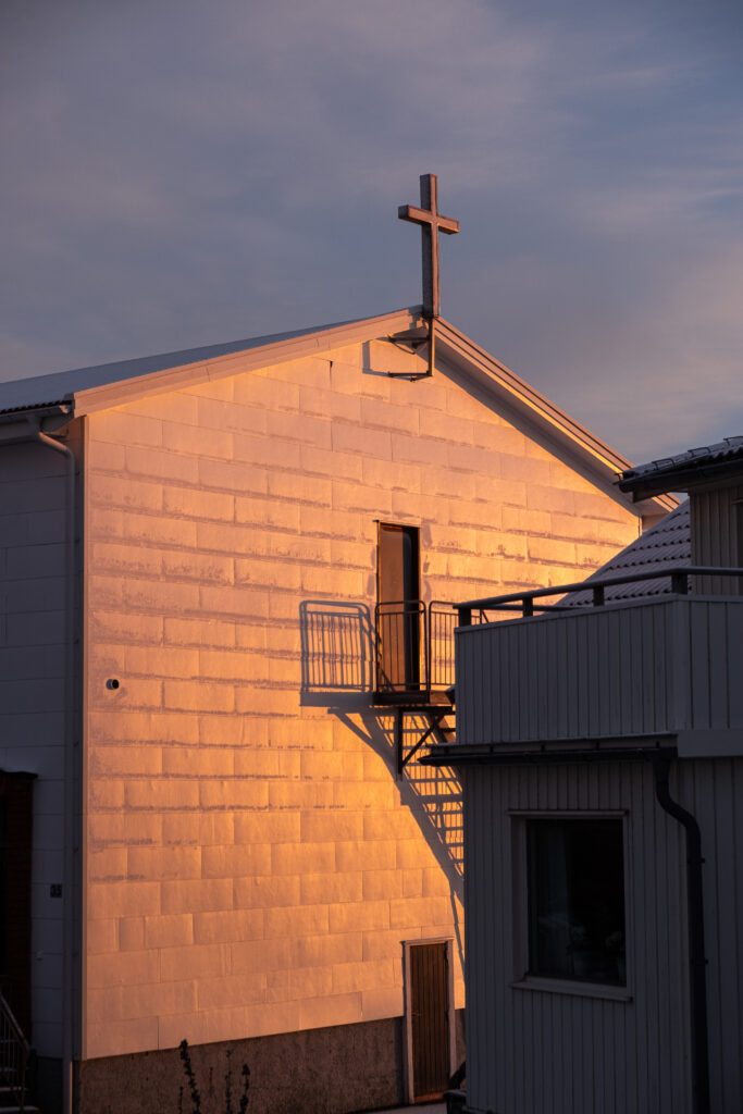 sun shining on a white house with a cross on the roof