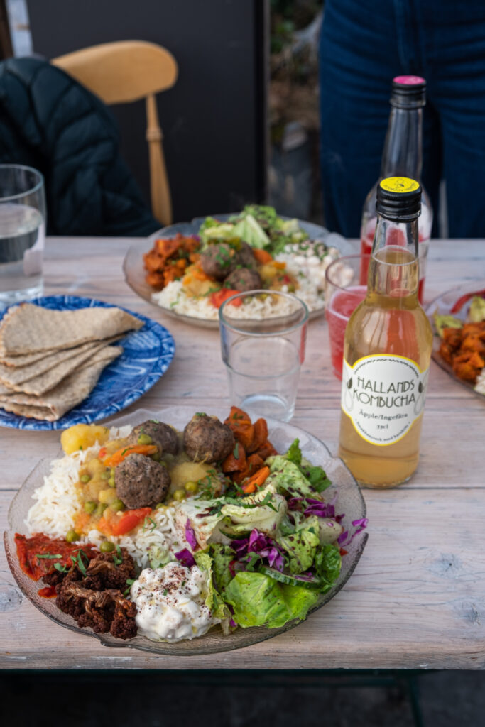 a plate filled with colourful food and hallands kombucha in a glass bottle served at skåra gårdsbakeri